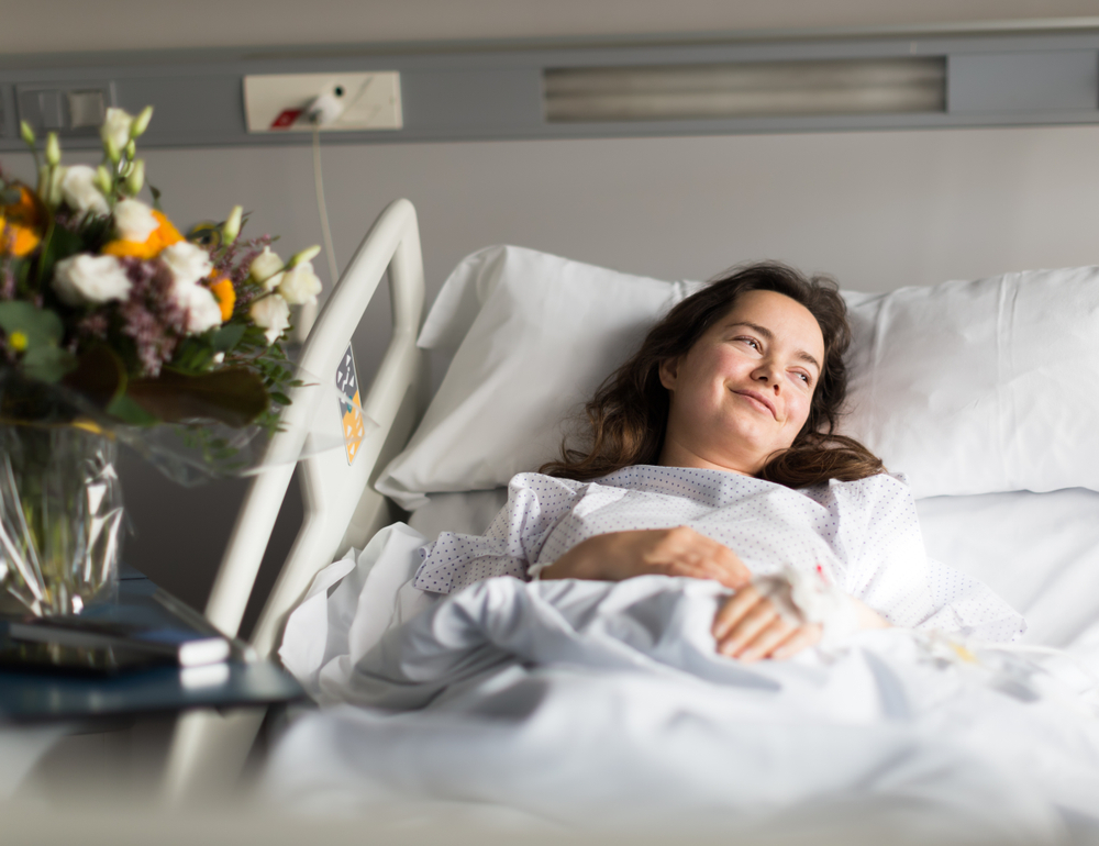 Adult woman is satisfied of visit her and lying on the bed in hospital indoor