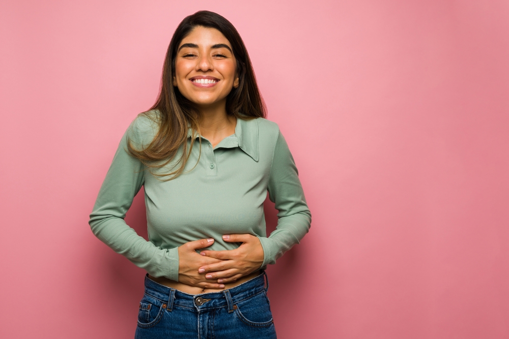 woman smiling and holding her stomach