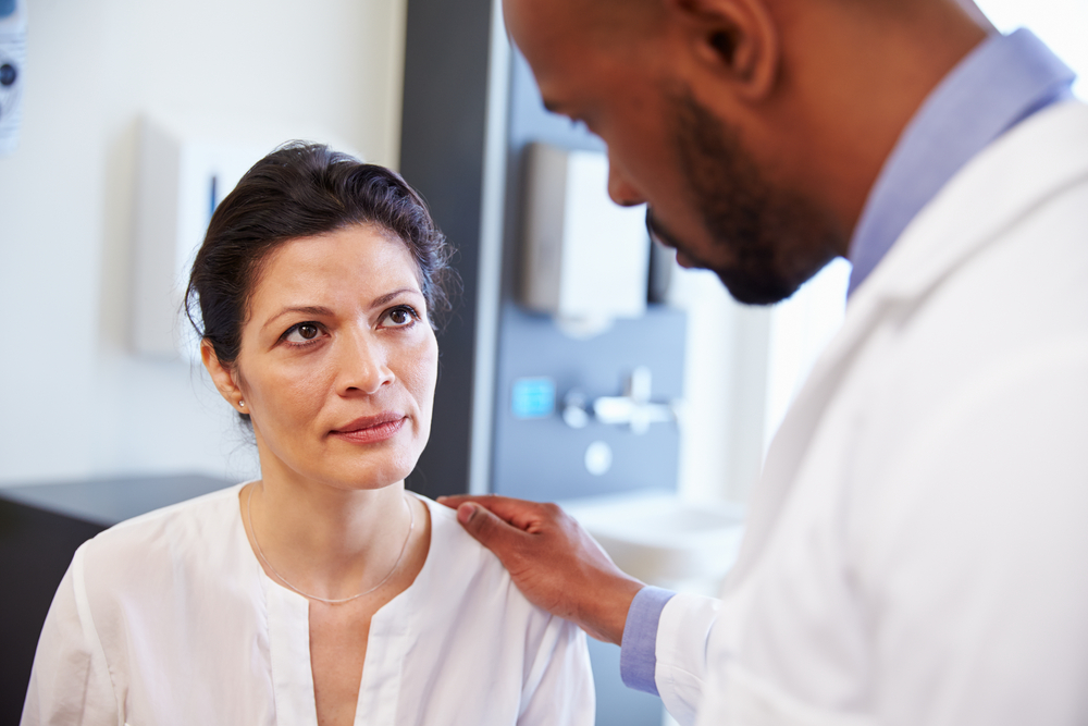 doctor talking to woman; woman listens intently
