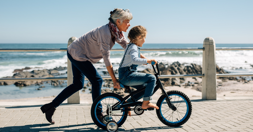 Woman pushing bike with grandchild.