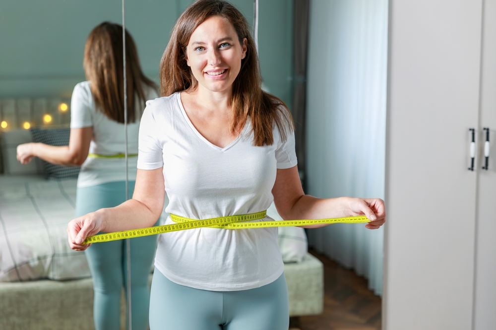 woman holding tape measure around waist.